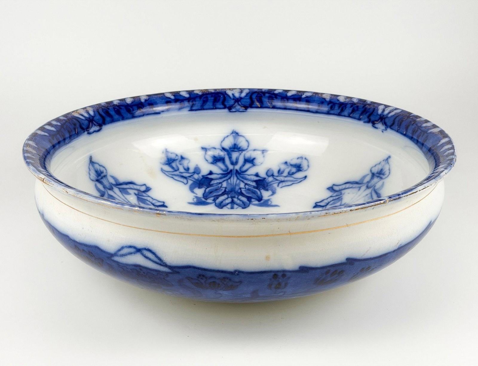 Antique Flow Blue Wash Bowl Basin, Myott Flora Art Nouveau Pattern: Large bowl features Flora pattern in burred transfer ware with gold accents. Approximately 5.25 in H x 17 in W x 17 in D. Weighs approximately 7 lbs 10 oz. LOCAL PICK UP INFORMATION: Wednesday, July 8