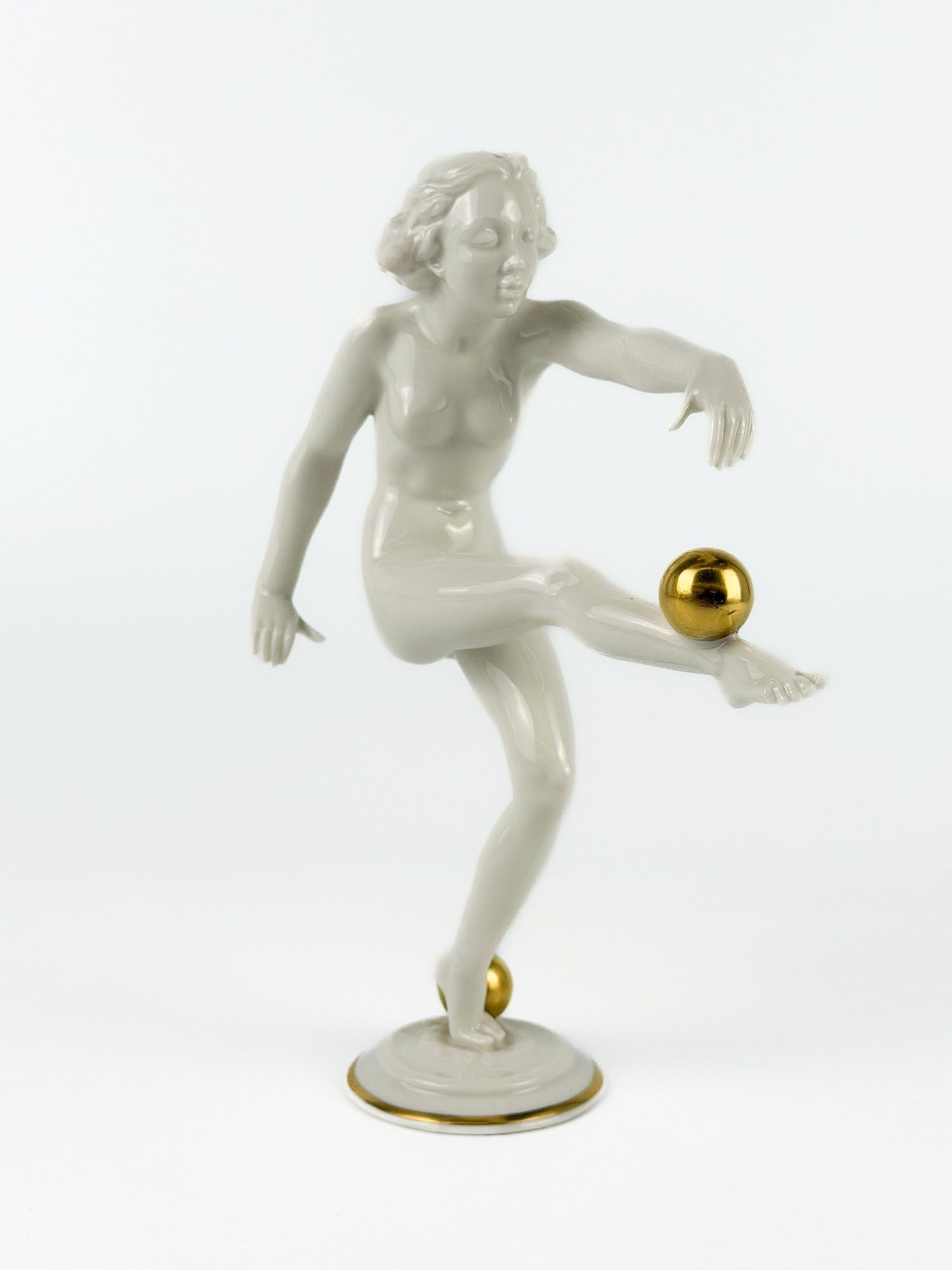 Hutschenreuther Art Deco Porcelain Nude Figure with Gold Accents: German Art Deco porcelain figure of a nude dancer, circa 1930s, modeled in glazed white (blanc de chine-style) porcelain. Stamp and label on bottom. Approx. dimensions: 8.5 in H x 7 in W x 3 in D