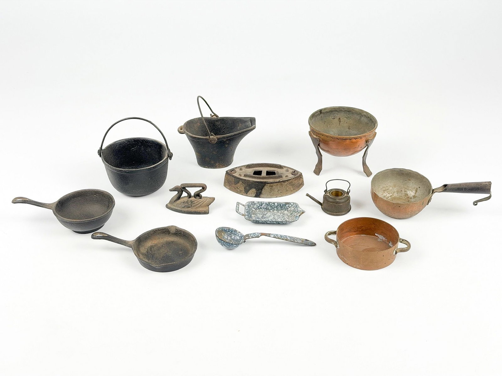 Collection of 12 Vintage Miniature Doll Cookware Items: Lot features various miniature pots, pans, and housewares made of cast iron, copper, or enamel. Variable size with the smallest being about 1.5 in H x 2 in W x 1.25 in D and the largest being approxim