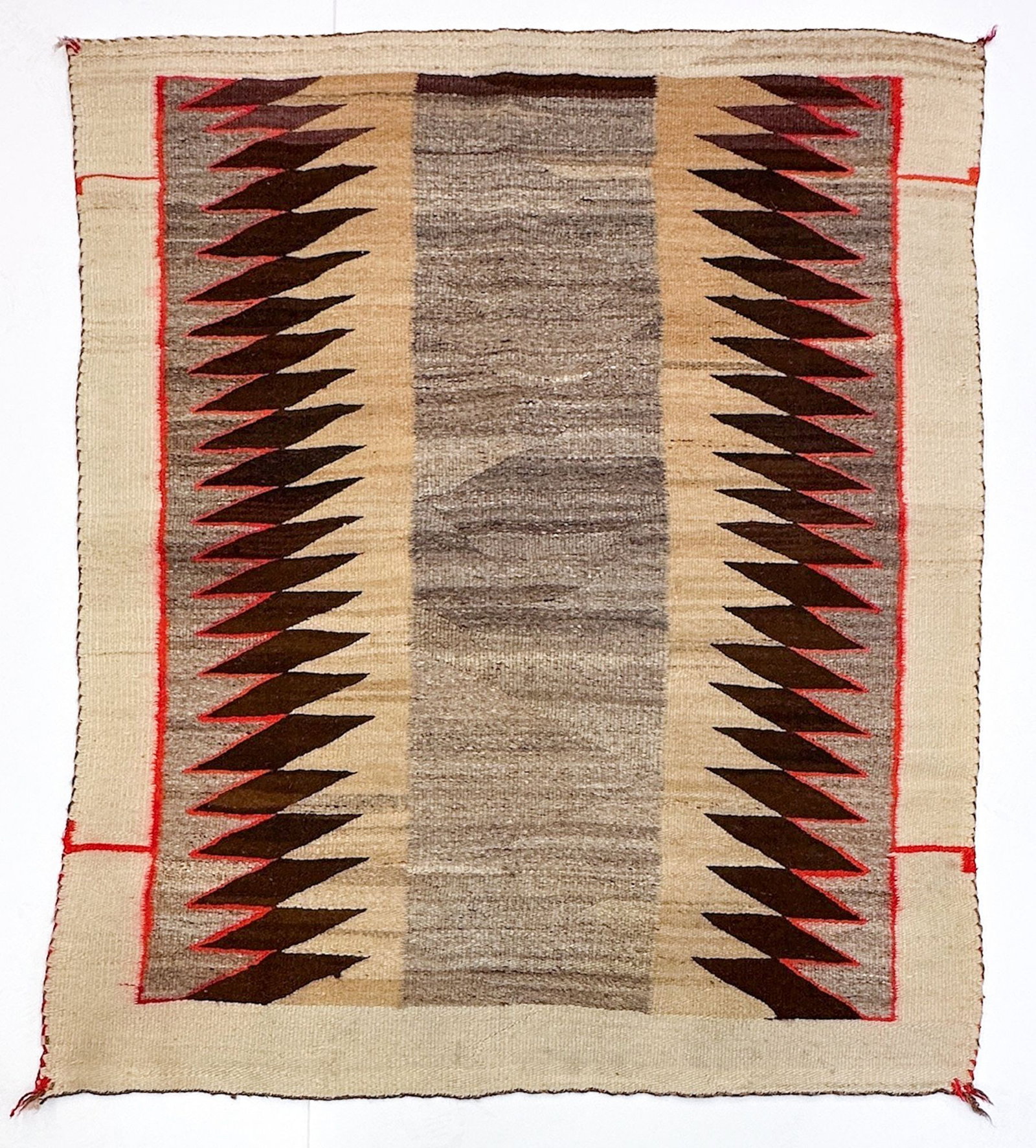Navajo Single Saddle Blanket / Rug, Serrated Sawtooth Design: Geometric design with beige, brown, red and gray tones. Red wool corner tassels. First half 20th century. Rug is approx. 58 in H x 49 in W. Weighs 6 lbs. LOCAL PICK UP INFORMATION: Wednesday, July 8, 