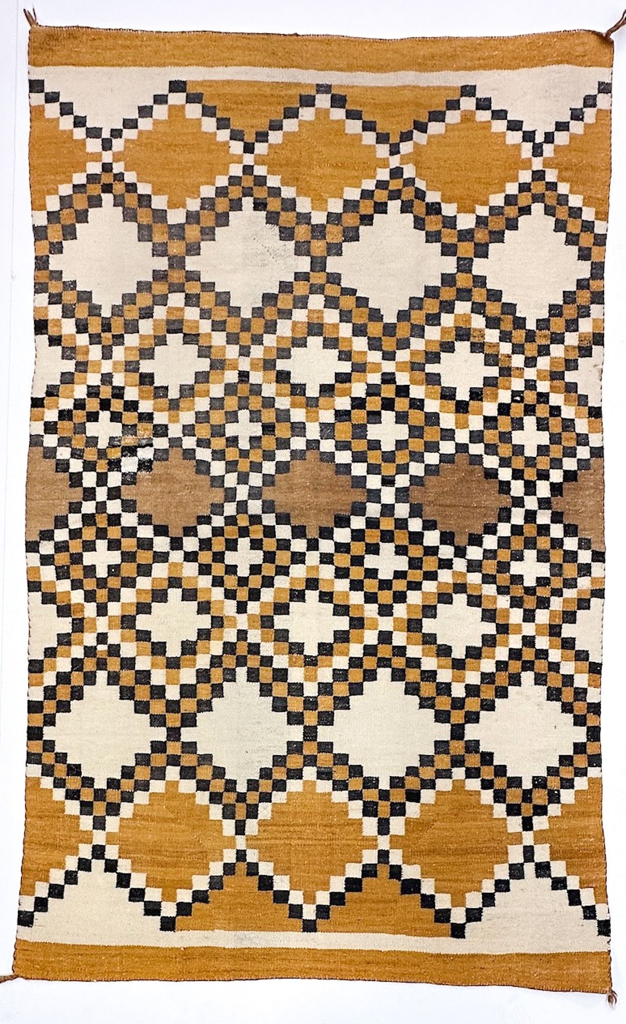 Navajo Saddle Blanket / Rug with Checkerboard Beaded Lattice Design: Beige, brown and yellow tones. Tassles on corners. Dimensions: 72 in H x 43.5 in W. Weighs 4 lbs 7 oz. LOCAL PICK UP INFORMATION: Wednesday, July 8, 10:00 AM - 2:00 PM 8059 Foothill Blvd, Sunland, CA 
