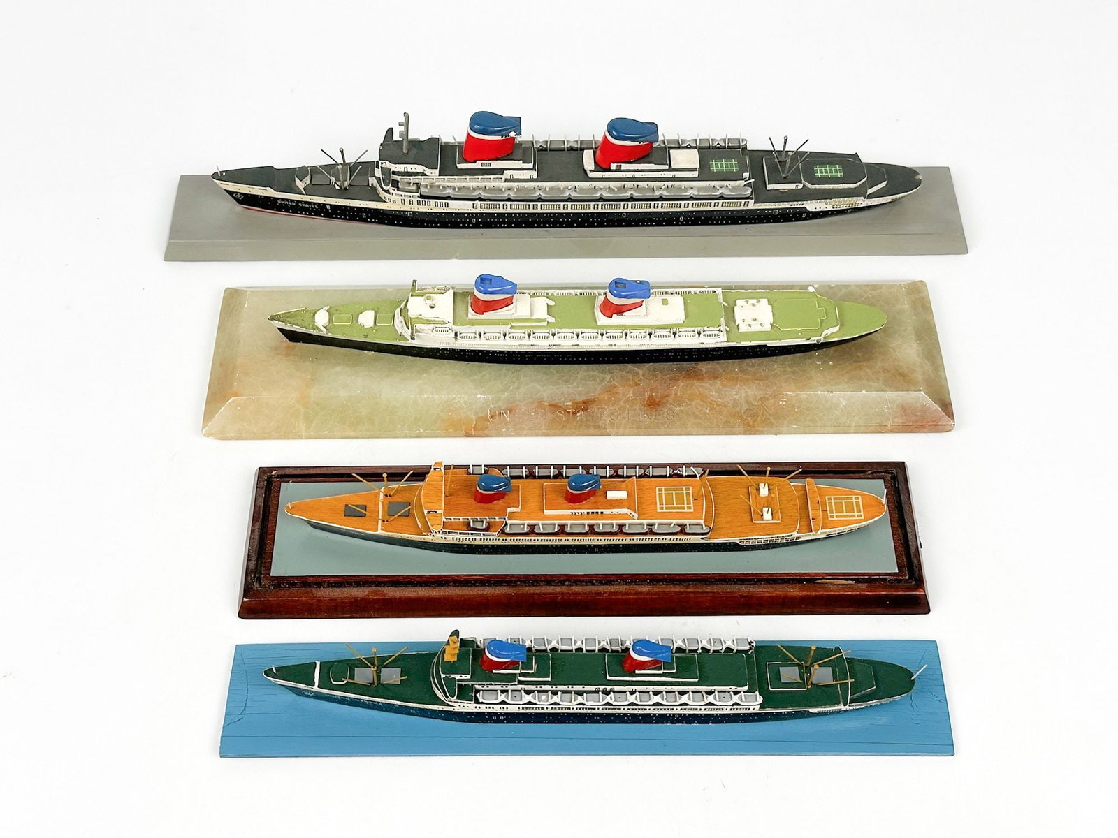 Group of 4 United States Lines Model Ships on Bases, SS United States, America: Group of 4 United States lines ship models. All are made of wood except the metal one on stone base. Smaller SS United States model with blue base has by Spielzeugbau Riwag (Richard Wagner) & made