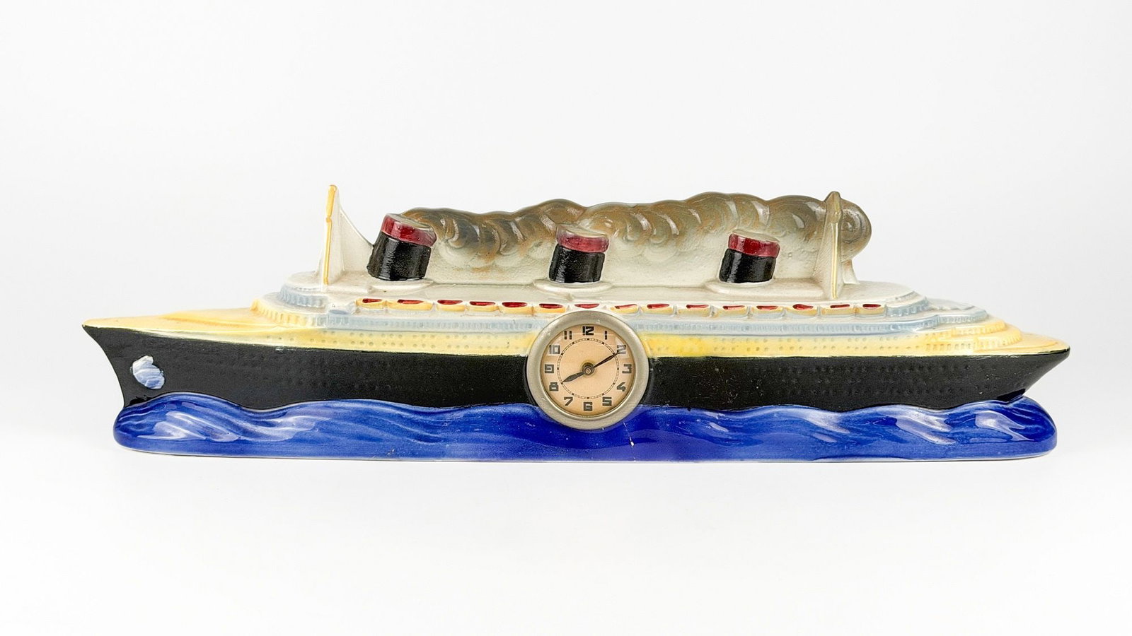SS Normandie Souvenir Glazed Ceramic Figural with Mechanical Clock: Souvenir glazed ceramic figural of the Normandie at sea with mechanical clock inset. Comparable to Christie's 2004 example. Dimensions: Approx. 5.75 in H x 21 in W x 3 in D. Weighs 3 lbs 2 oz.