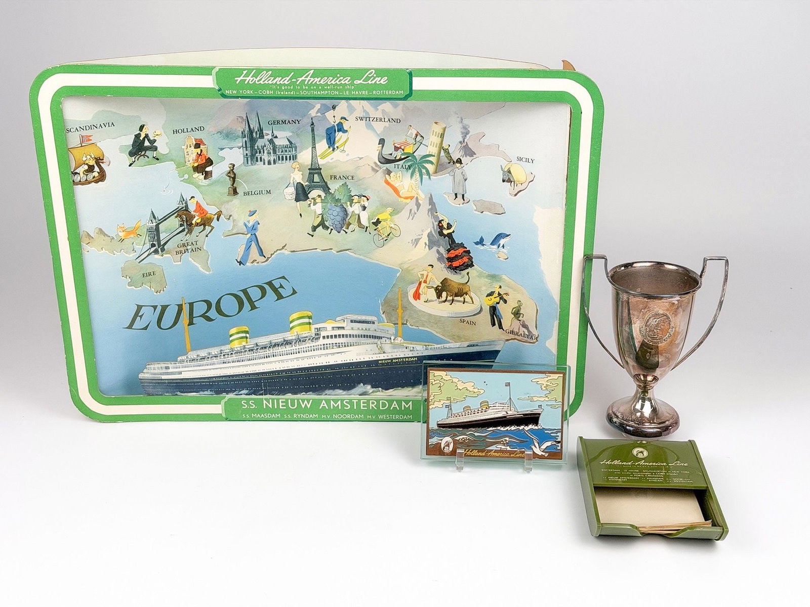 Lot of Vintage Ephemera from the Holland-America Line: Lot includes a chipboard diorama, souvenir enamel and copper artwork on glass, silver (800) handled trophy, and plastic note dispenser. Dimensions: tems range in size from approximately 3.5 in H x 5.2