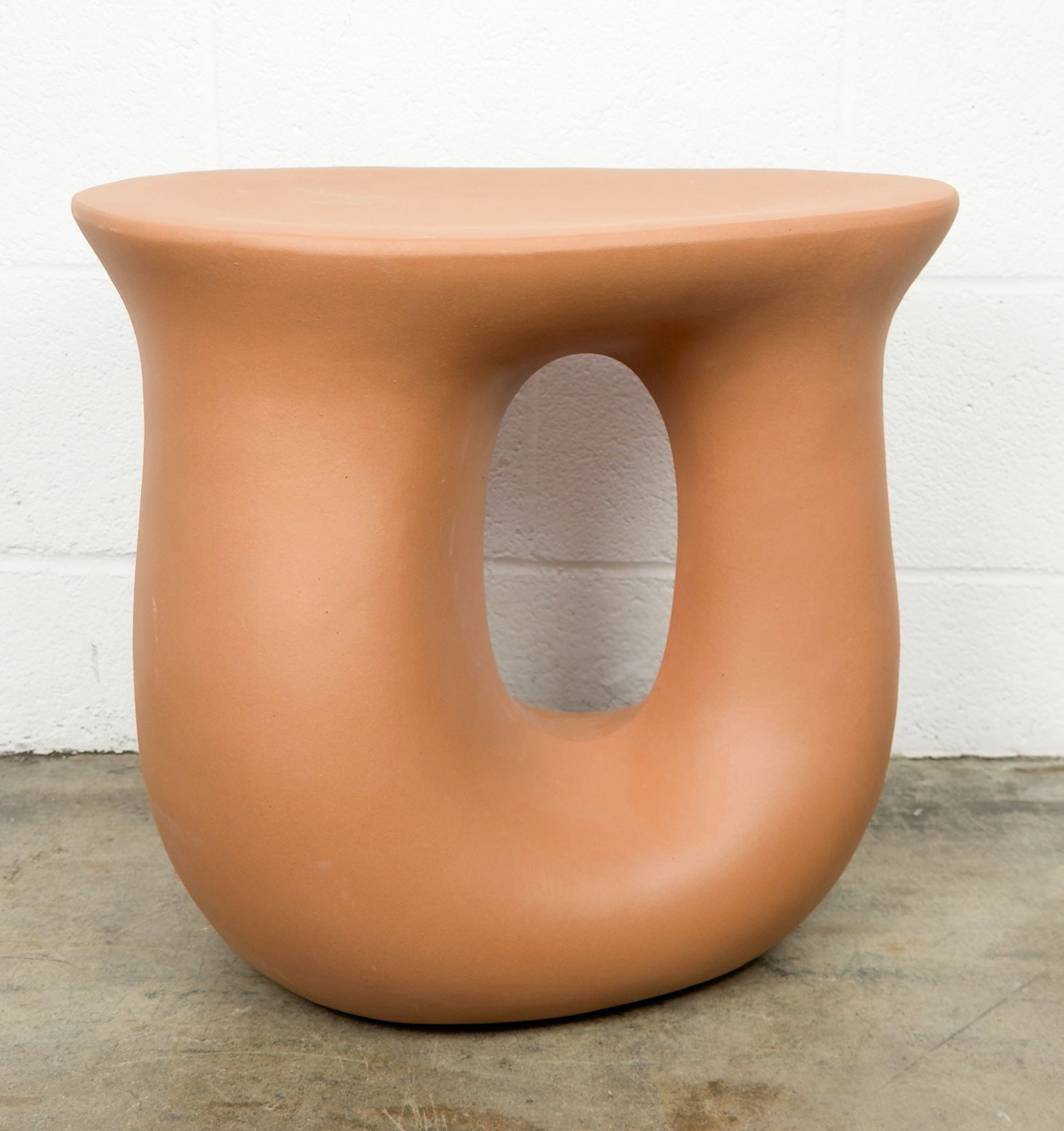 Vera Ceramic Curved Side Table with Abstract Design: Unglazed ceramic table features abstract design with a hole in the center. Dimensions: Approximately 17 in H x 18.25 in W x 12 in D. Weighs approximately 25 lbs. LOCAL PICK UP INFORMATION:Wednesday,