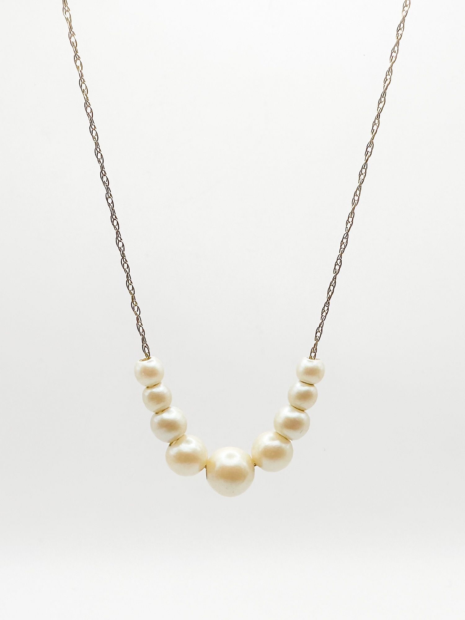 14K Gold Pearl Graduated Pendant Necklace: 14K yellow gold necklace featuring a graduated pearl pendant with nine pearls. Marked Butterfly on clasp. Dimensions: Measures 18 inches long and weighs 1.9 grams. LOCAL PICK UP INFORMATION:Wednesday,