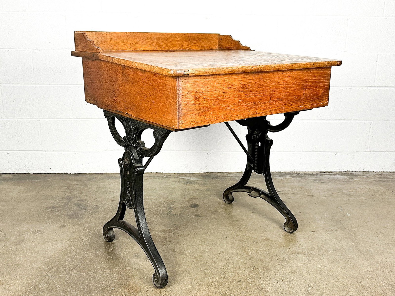 Antique Oak and Cast Iron School Desk with Pencil Tray: Cast iron legs. Beautiful oak grain. Pencil tray. Hole on table top. Name tag holder on back. Dimensions: Desk is approx. 33.25 in H x 30 in W x 28.25 in D. LOCAL PICK UP INFORMA