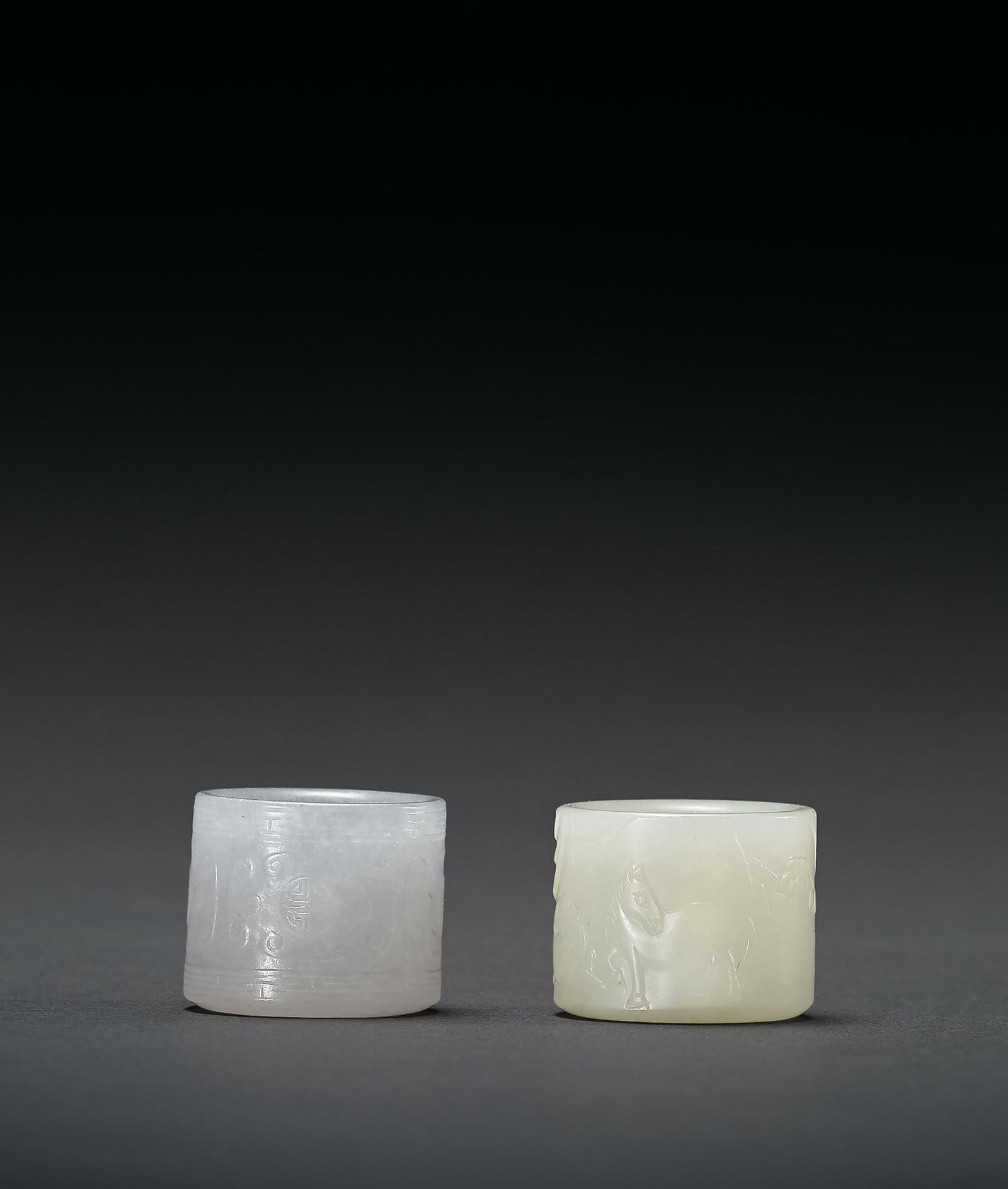 Jadeite 'Cloud' Archer's Ring and A White Jade 'Horse' Archer's Ring, Qing Dyn.: 188 清 翠玉勾連雲紋扳指、白玉雙馬扳指 二件一組 H2.3cm 翠玉扳&#