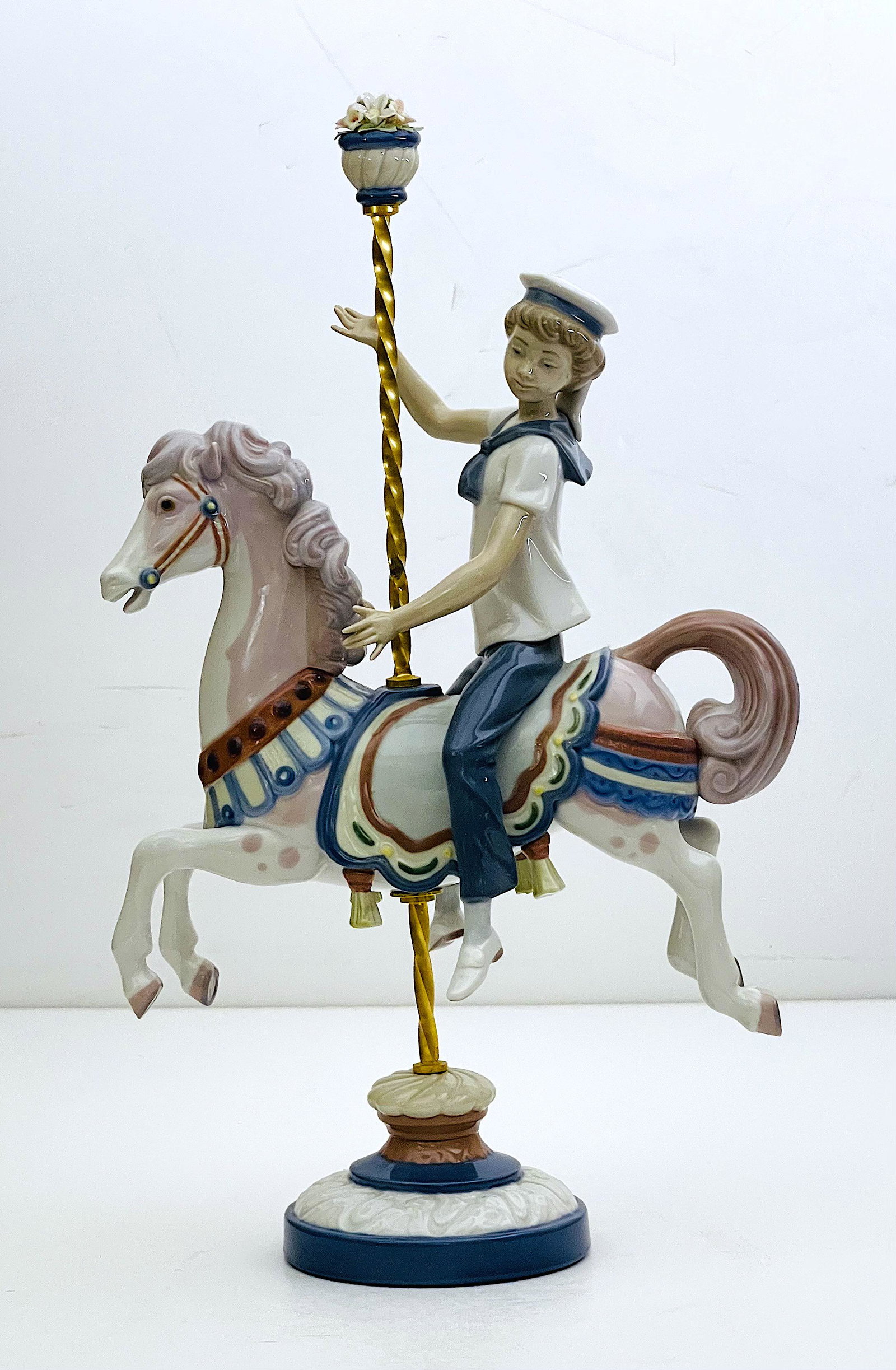 Boy on Carousel Horse Lladro Porcelain: Lladro Porcelain, Glazed, Boy on top of decorated toy horse. Flower stopper on top of pole. Artist: Jose Puche, ca. 1985-2000, Dimensions: 15"H x 9"W. Made in Spain.