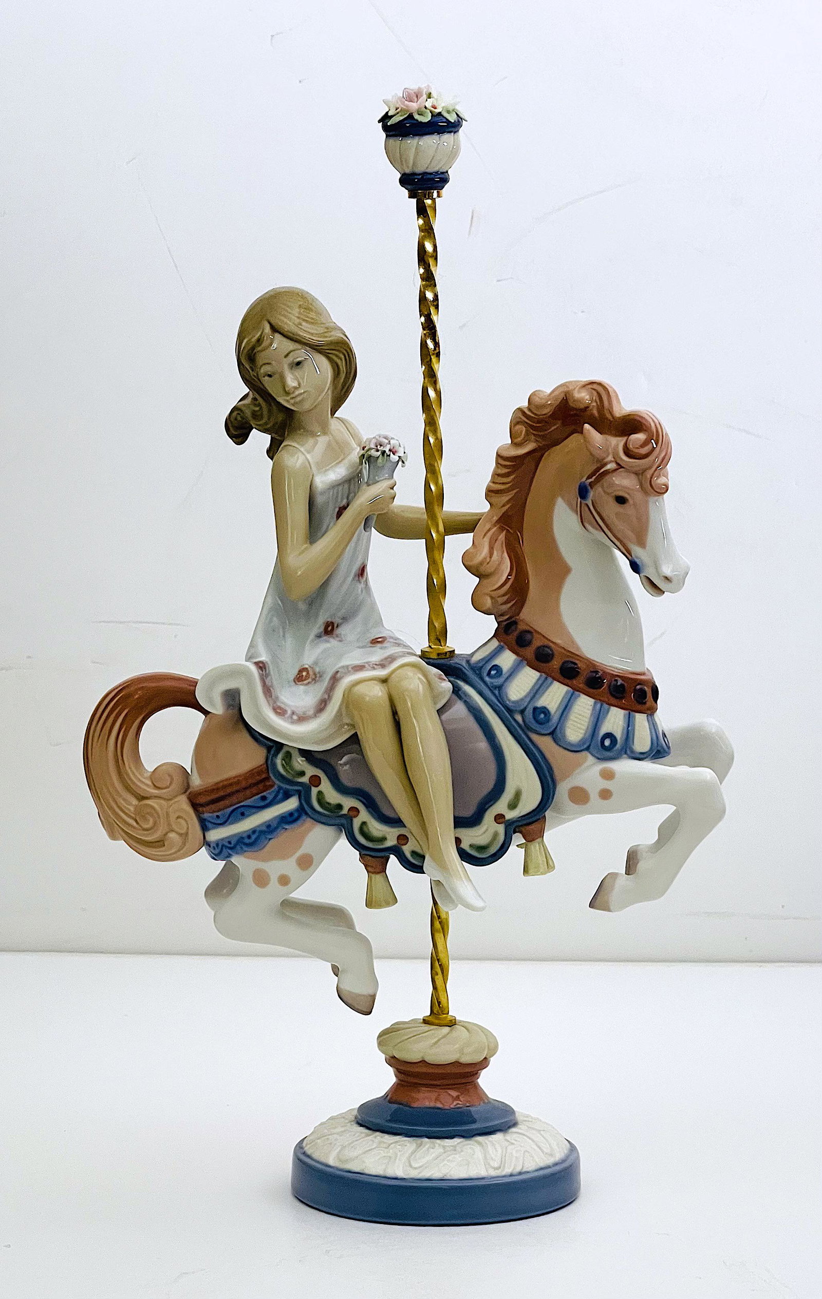 Girl on Carousel Horse Lladro Porcelain: Lladro Porcelain, Glazed, Girl on top of decorated toy horse. Flower stopper on top of pole. Artist: Jose Puche, ca. 1985-2000, Dimensions: 15"H x 9"W. Made in Spain.