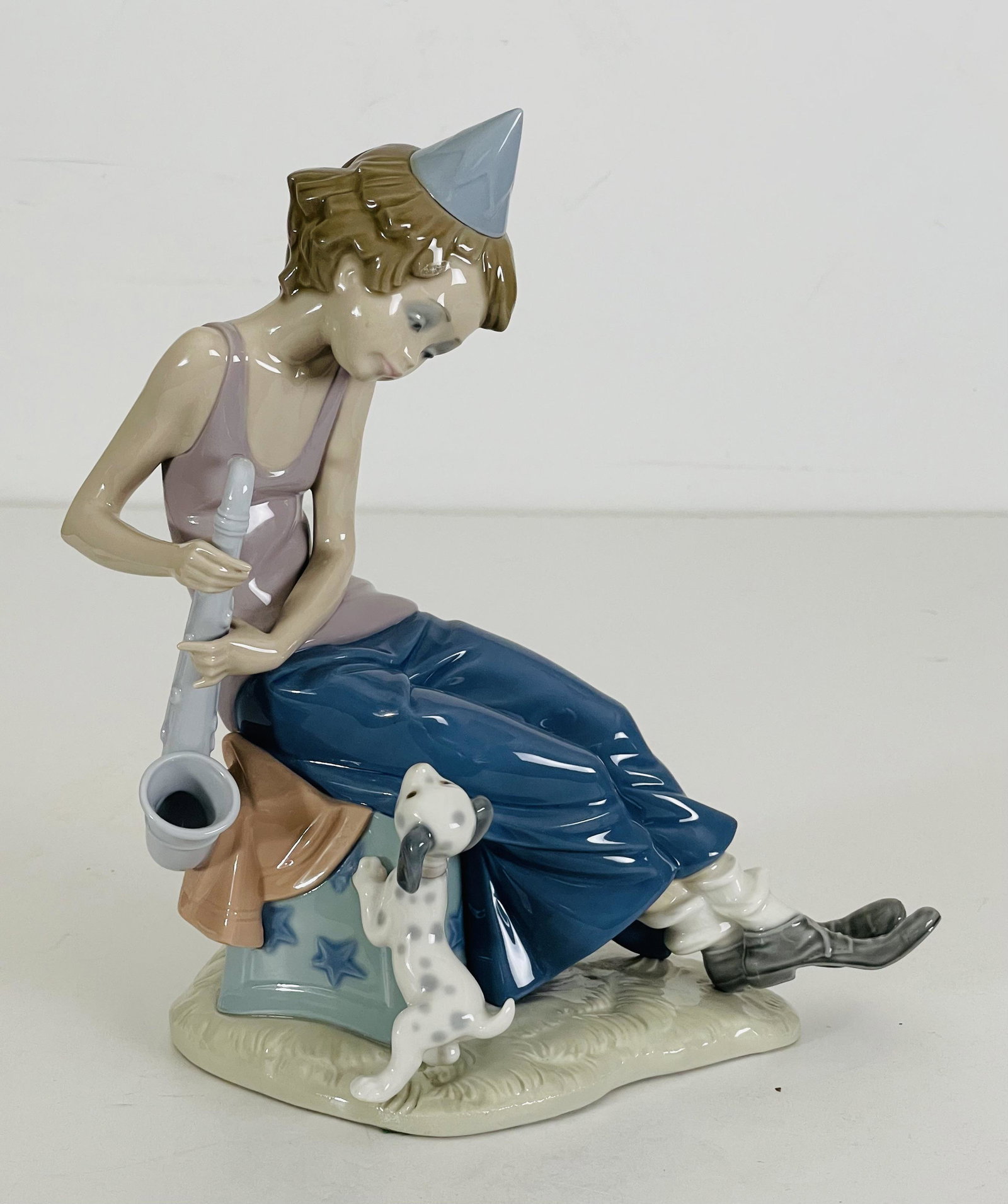 Lladro Porcelain Clown Boy with Saxophone and Dog: Lladro Porcelain Clown Boy with Saxophone and Dog Figurine, 10.25" H x 8.55" W x 5.75" D (in). Made in Spain.