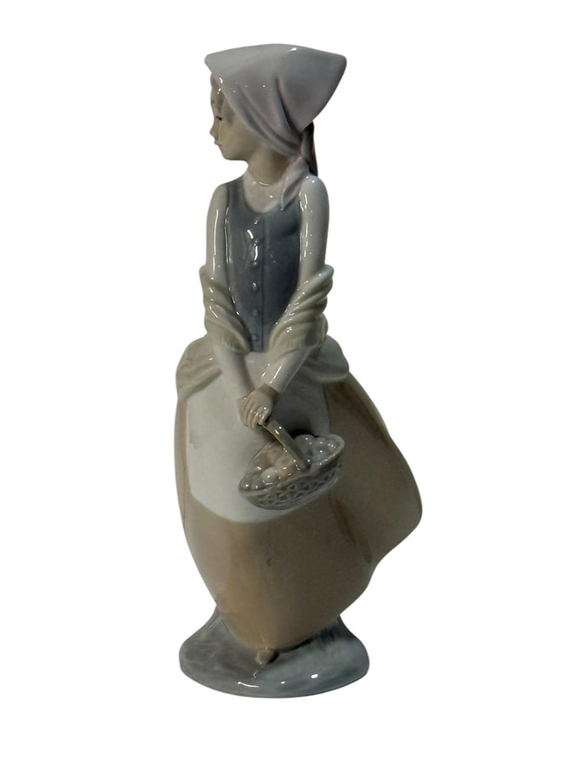 Windswept Girl with Basket, NAO by Lladró 4834.: NAO by Lladro Collection, Windswept Girl with Basket, NAO, porcelain with a glazed finish. Ref. 4834. Sculptor Antonio Ramos. Measurements: 9.50" high x 5.50" wide (inches). In perfect state. With ori