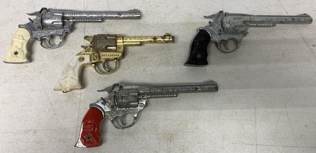 lot of 4 Kit Karson Toy Cap Guns: all are cast metal with plastic hand grips, one red grip is damaged, all have wear