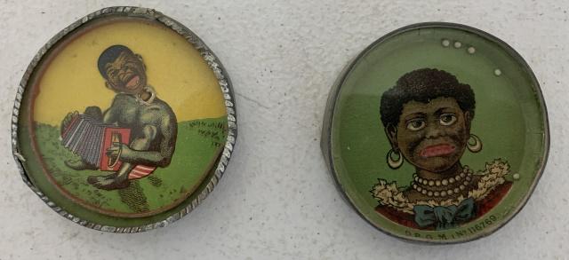 2 black art dexterity puzzle/pocket mirrors: man playing accordian has cardboard separation inside and rim is corroding, woman marked D.R.G.M. 116769 has heavy mirror loss