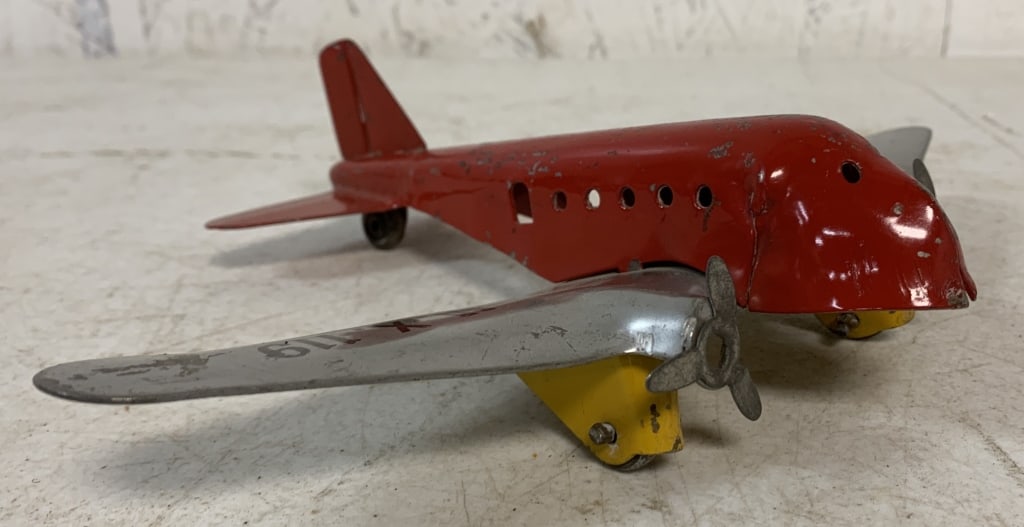 Pressed Steel Airplane: heavy material, most likely pressed steel, stamped made in the USA, no other markings, red paint chipped and worn at a number of spots, discoloring of the wing