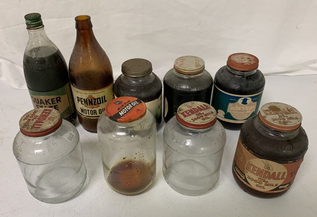 9 glass motor oil jars; 5 are full: paper labels have wear with fading, stains and small tears