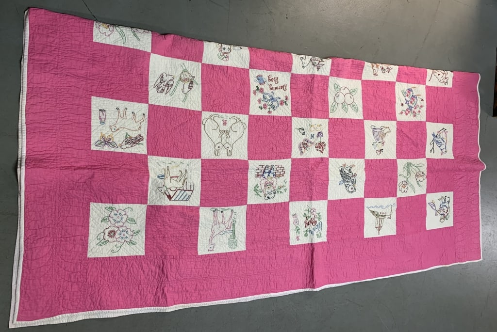 quilt with needlework: 83" x 80"; has wear with some staining and damage as shown on backside