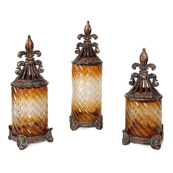 Fleur De Lis Canister Set of 3: The Fleur de Lis Canister set makes a beautiful presentation on any shelf or countertop. Featuring ornate details a perfectly hand burnished finish and spiral wave amber glass. Each canister top remov
