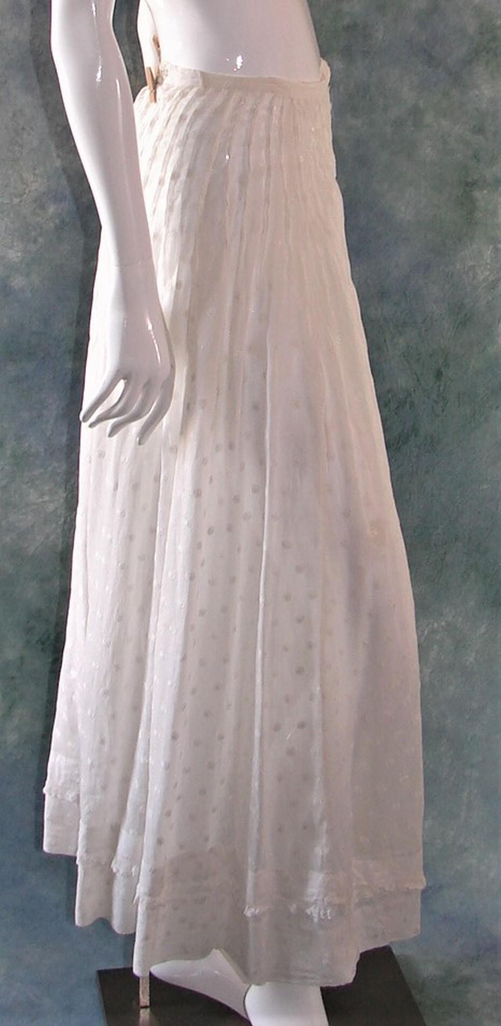 Ladies Edwardian Trained White Lawn Bustle Skirt with: White law skirt covered with hundreds of small embroidered flowers, pin tucks around the waist, closes with two hook and eyes, measures 22" w x 35" l in the front and 38" back