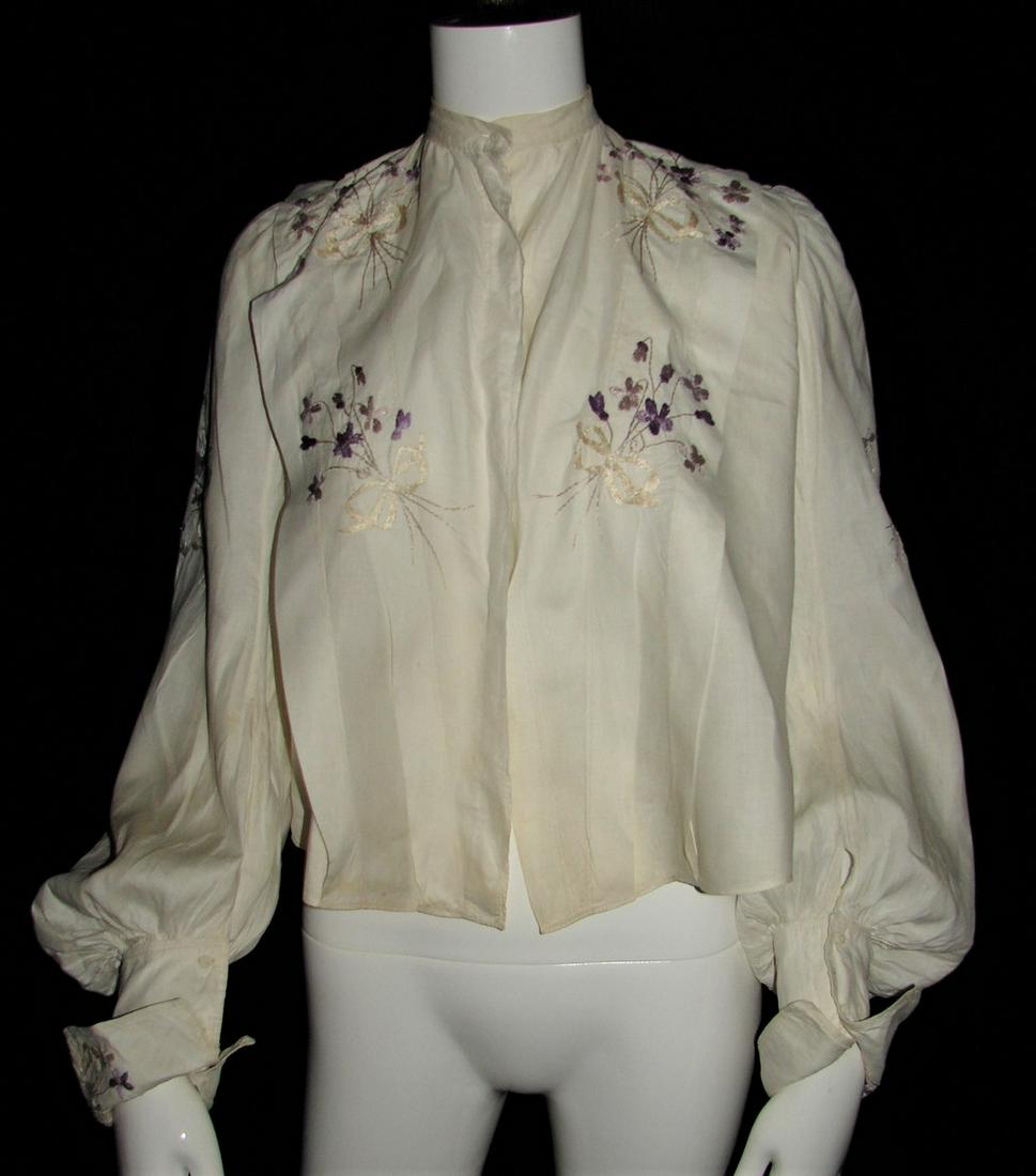 1907 Edwardian Blouse White Cotton with Purple and Gold: gold embroidered bows on bodice, back and sleeves, two purple colors of embroidered flowers, pleats in front and back, folded sleeves, embroidered cuffs, gathered sleeves, four hidden front buttons, 2