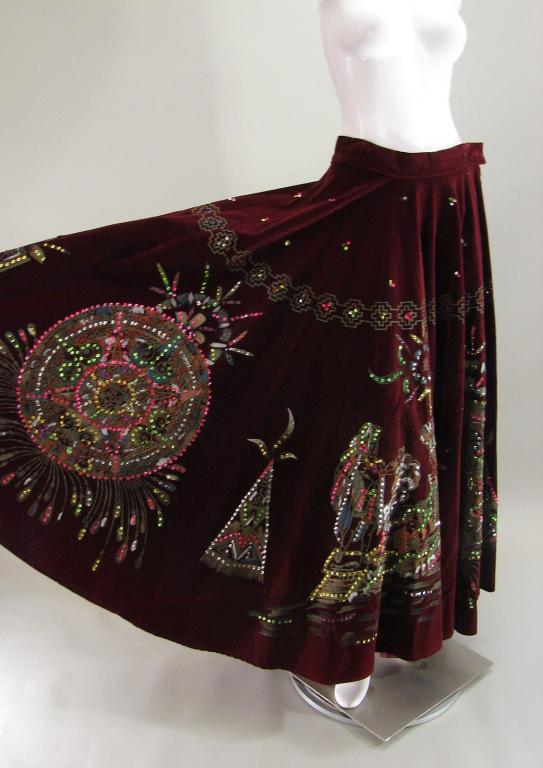 1970s South American Souvenir Skirt: Velvet like fabric with painting or applied paint and sequins, theme is Mayan or Aztec characters in sacrifice scenes, large calendar like medallion and other symbols, closes with small zipper and but