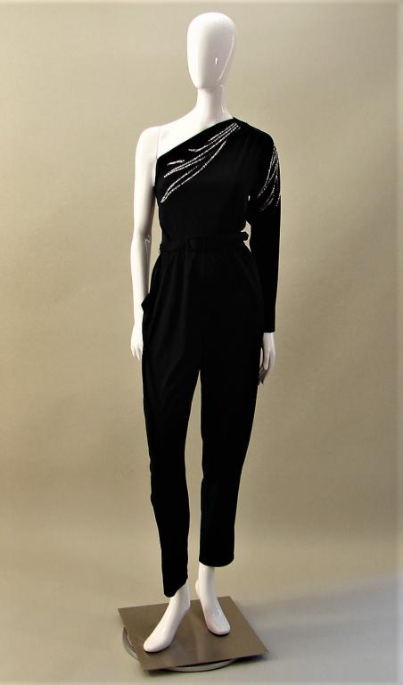 70s Black Jersey Jumpsuit: Jersey black jumpsuit, off the shoulder with silver glitter design on the bodice and arm, has 2 pockets, original belt, and closes with a side zipper 53" L x 36" B x 26" elastic waist x 29" inseam