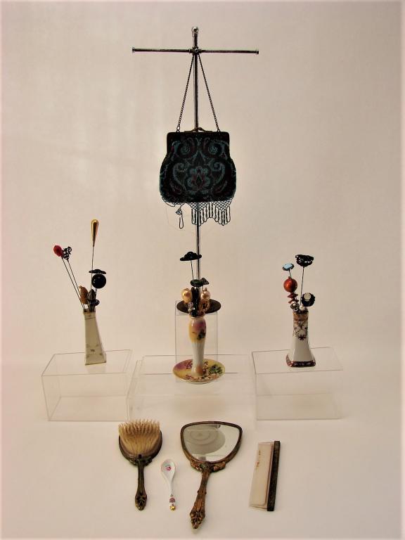 Victorian Boudoir, Hat Pins, Etc.: 1) Porcelain vase with 10 hat pins.2) Limoge porcelain vase with 8 hat pins3) Hand painted Nippon hat pin stand with 7 hat pins4) Brush and mirror5) Comb6) Ceramic spoon7) Beaded purse with leather in