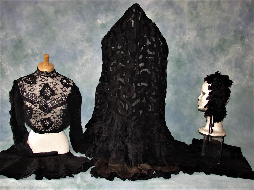 5 Pc Edwardian Mourning Ensemble: As-Is, consisting of 5 pieces: tape lace netted skirt with silk flounces and ribbon work, 2 black petticoats in taffeta, black lace blouse, and a scarf for the head or neck. Silk and silk velvet headp