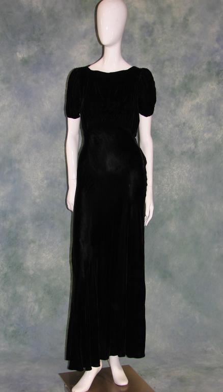 1930s Bias Cut Black Velvet Gown: Black velvet bias cut gown with a self belt, panel of tiny gathers in the bodice, short puffy sleeves. Measures 58" long x 36" bust x 32" waist x 34" hips. Slips over the head and has metal snaps on t