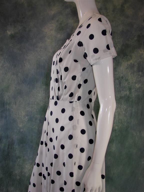 1940s Blue & White Polka Dot Dress: Folded down collar with buttons attached, pleats on the bodice, darts in the bust, and a metal zipper on the side. 43" L x 34" B x 26" W x 40" H
