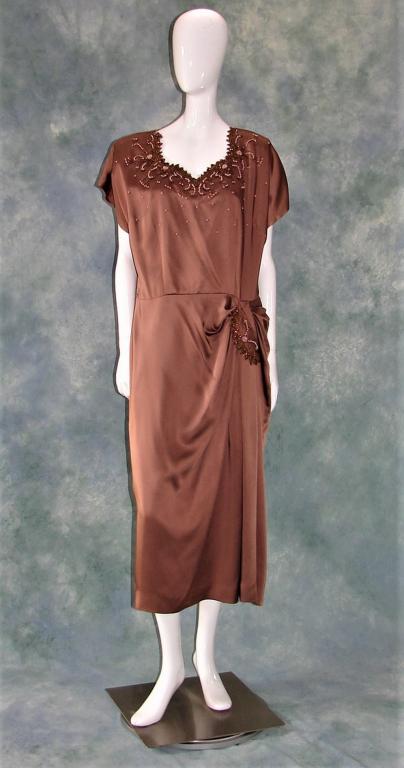 Vintage Lane Bryant Ladies Cocktail Dress: V neck covered with beads, pearls scattered on bodice, darts on bust, gathered and pleated below the waist with attached embellishment, measures 50"L X 46"B X 38"W X 46"H X 18" shoulder to shoulder