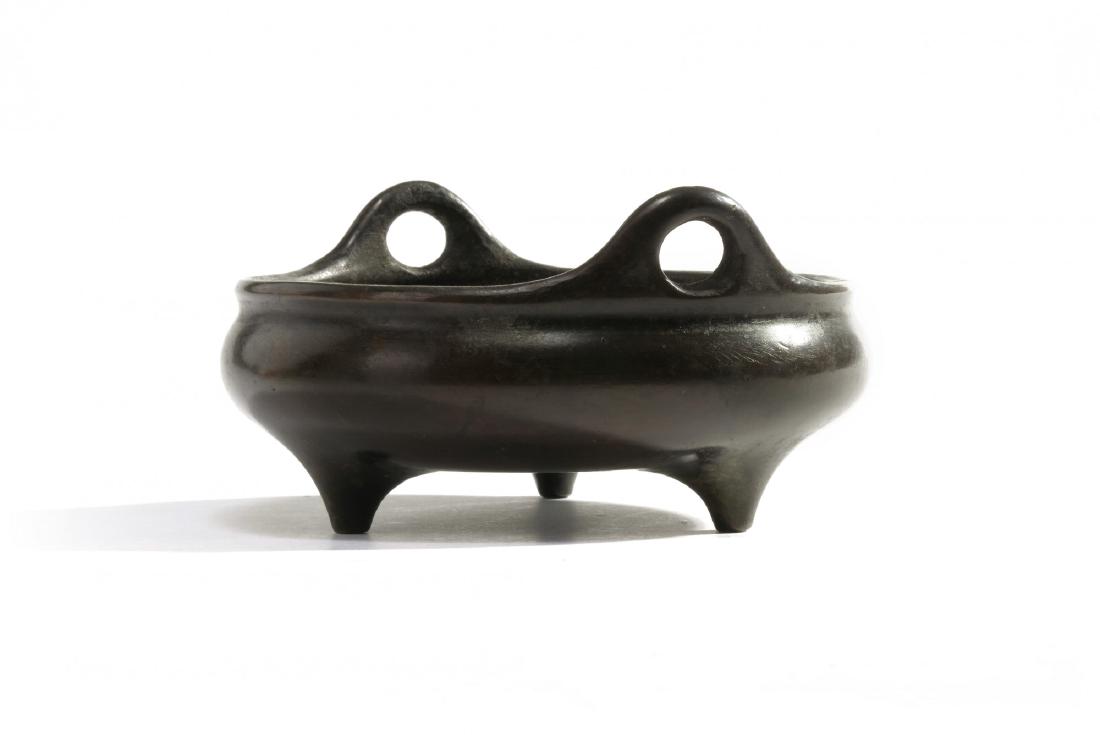 A Chinese bronze tripod censer: The censer is fashioned with two upright strap handles, the base is marked with an impressed ‘yu tang jing wan’ seal mark. Condition: Minor dents Origin: China Period: 17th-18th century Sizes: 8.0
