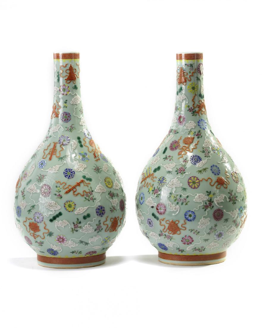 A pair of Chinese famille rose celadon-ground: Each vase is decorated in white slip with bats and clouds highlighted by incised details, all amongst scattered iron-red and gilt Buddhist Emblems and attributes of the Eight Immortals. The neck and f