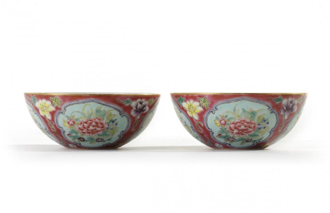 A pair of Chinese ruby-ground famille rose 'floral': Each bowl is finely painted with four panels depicting enclosing flower sprays, divided by further flower sprays, all reserved against a ruby ground. Each base with an apocryphal Yongzheng mark. Condi
