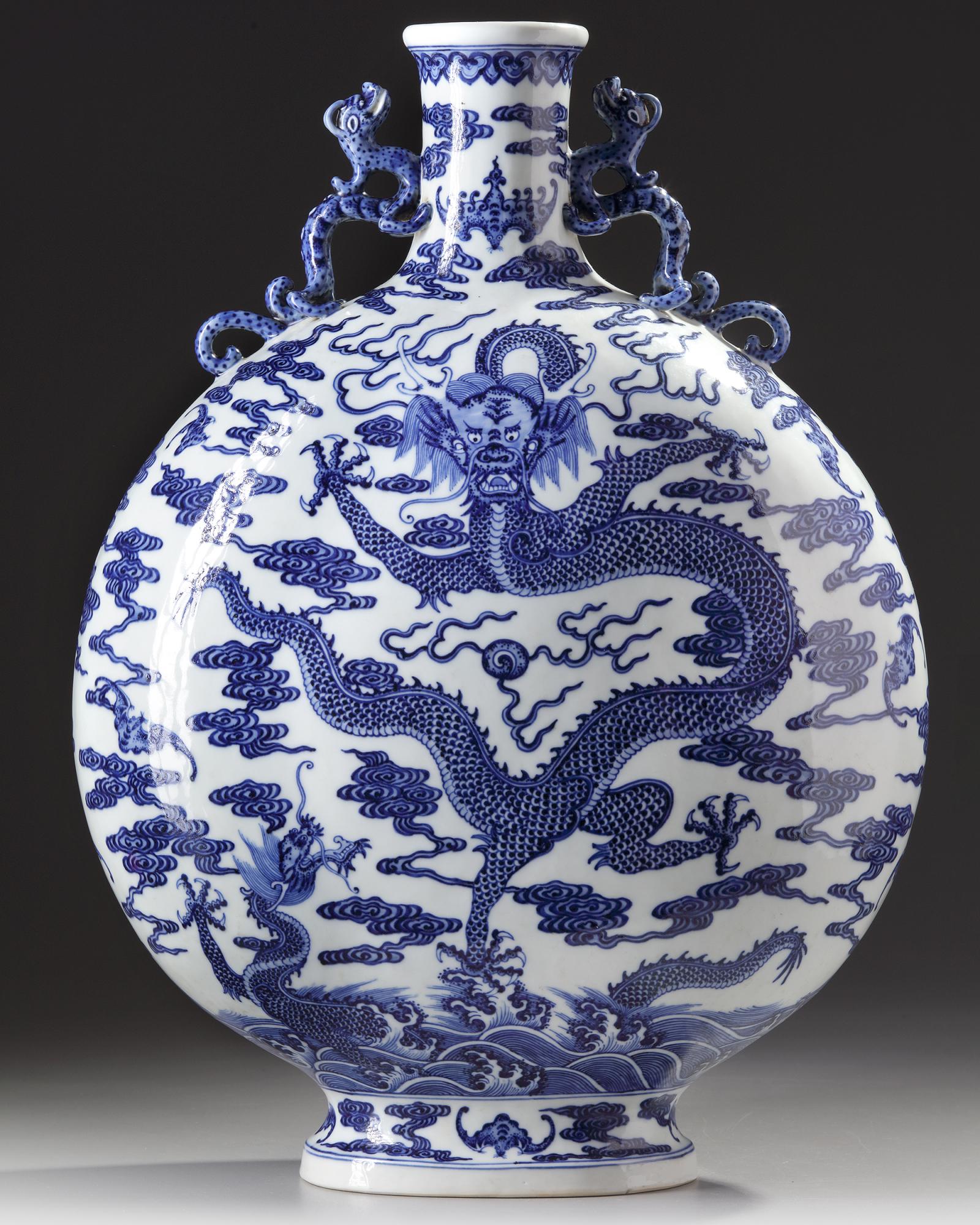 A LARGE CHINESE BLUE AND WHITE 'DRAGON' MOONFLASK: The moonflask is decorated with two moulded dragon handles at the neck flanking a bat. Each of the sides is decorated with a front-facing dragon chasing the flaming pearl amongst cloud scrolls, all ab