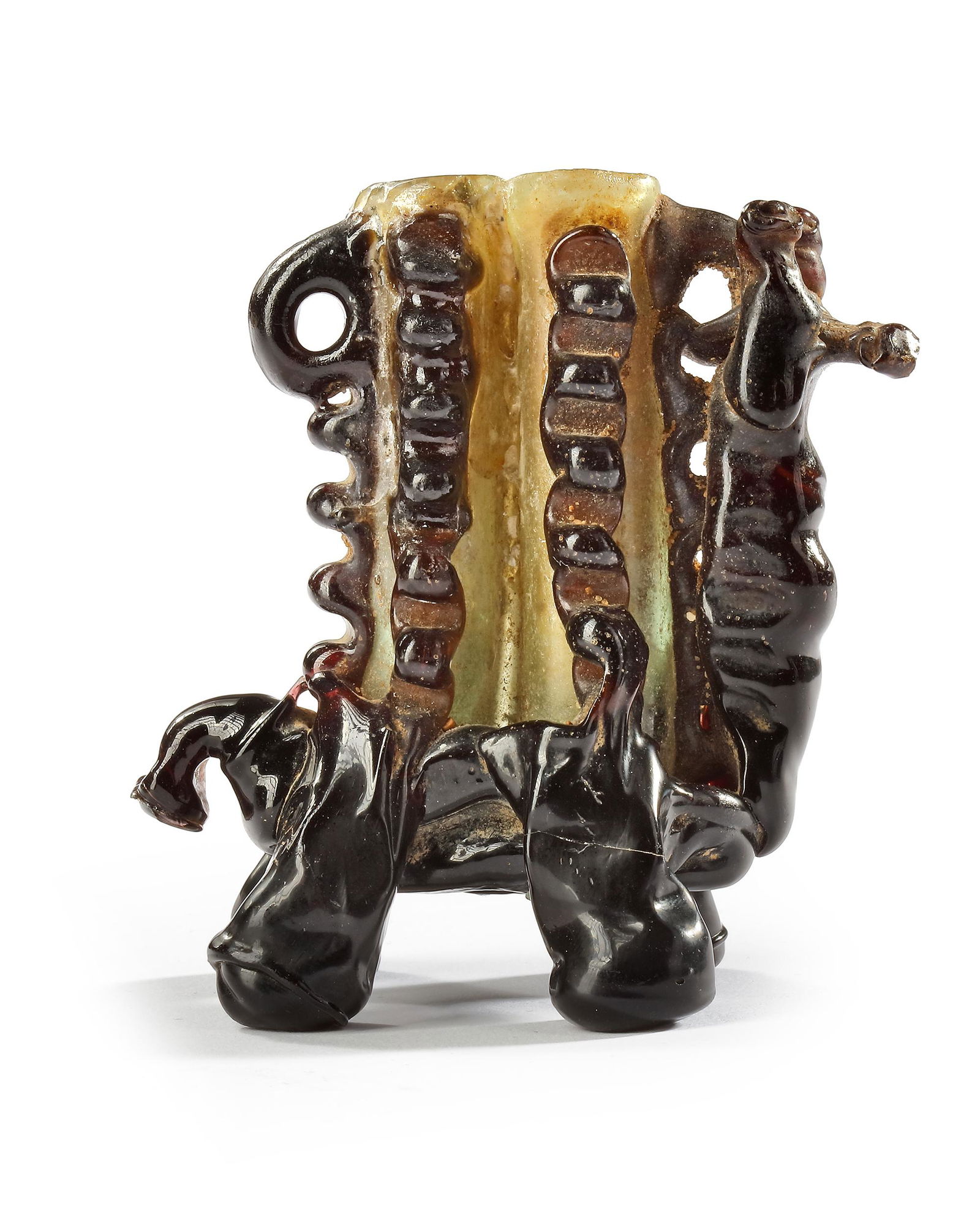 A FINE AND RARE COLORED GLASS ANIMAL FORM UNGUENTARIUM, SYRIA, 7TH-9TH CENTURY: With two free-blown tubular flasks of transparent colorless glass encased in trails of purple hot-worked glass in the form of rippling vertical flanges with two lug handles set on four naturalistic an