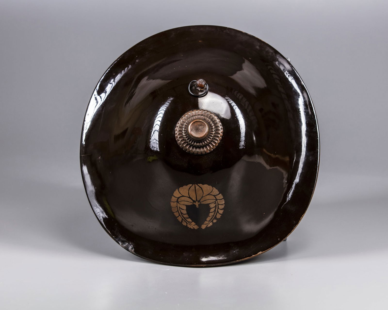 A JAPANESE LACQUER JINGASA (HELMET), LATE EDO: A Japanese lacquer jingasa (helmet) with family emblem. Height: 13 cm. Width: 32 cm. Appears to be in a good condition