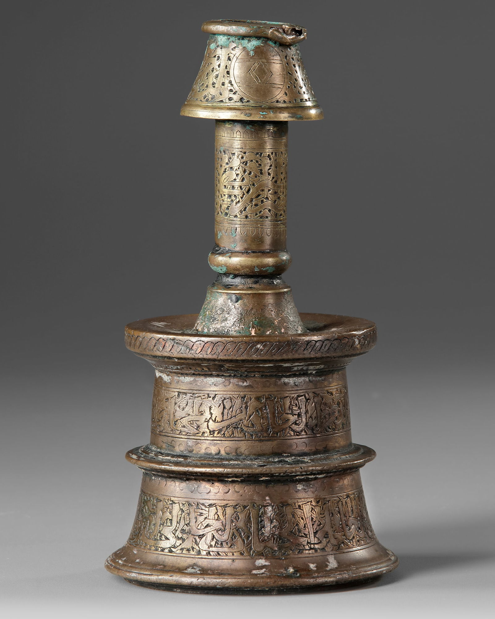 A CANDLESTICK, 14TH-15TH CENTURY: The base of truncated conical form encircled by two pointed ridges, the projecting shoulder leading to a concave driptray, the cylindrical neck surmounted by a broad socket tapering to the mouth, deco
