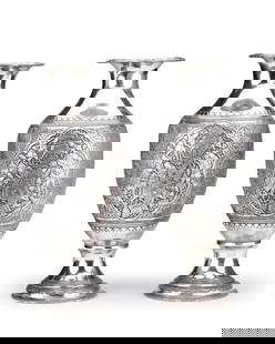 A PAIR OF AMPHORA SHAPED PERSIAN SILVER VASES, 19TH CENTURY: A pair of amphora-shaped, Persian, silver vases, with scenes of rural labor, feast and libation. Impressive and detailed objects. On the rim of the pedestal there are stamps: silver 84 and the master