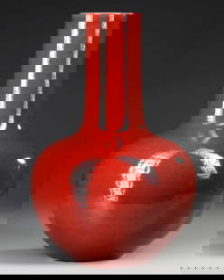 A LARGE CHINESE RED GLAZED BOTTLE VASE, 19TH-20TH CENTURY: The vase is shaped with a globular body and a cylindrical neck. It is covered with a strawberry-red glaze thinning slightly at the rim and stopping neatly at the foot. Height: 51 cm.
