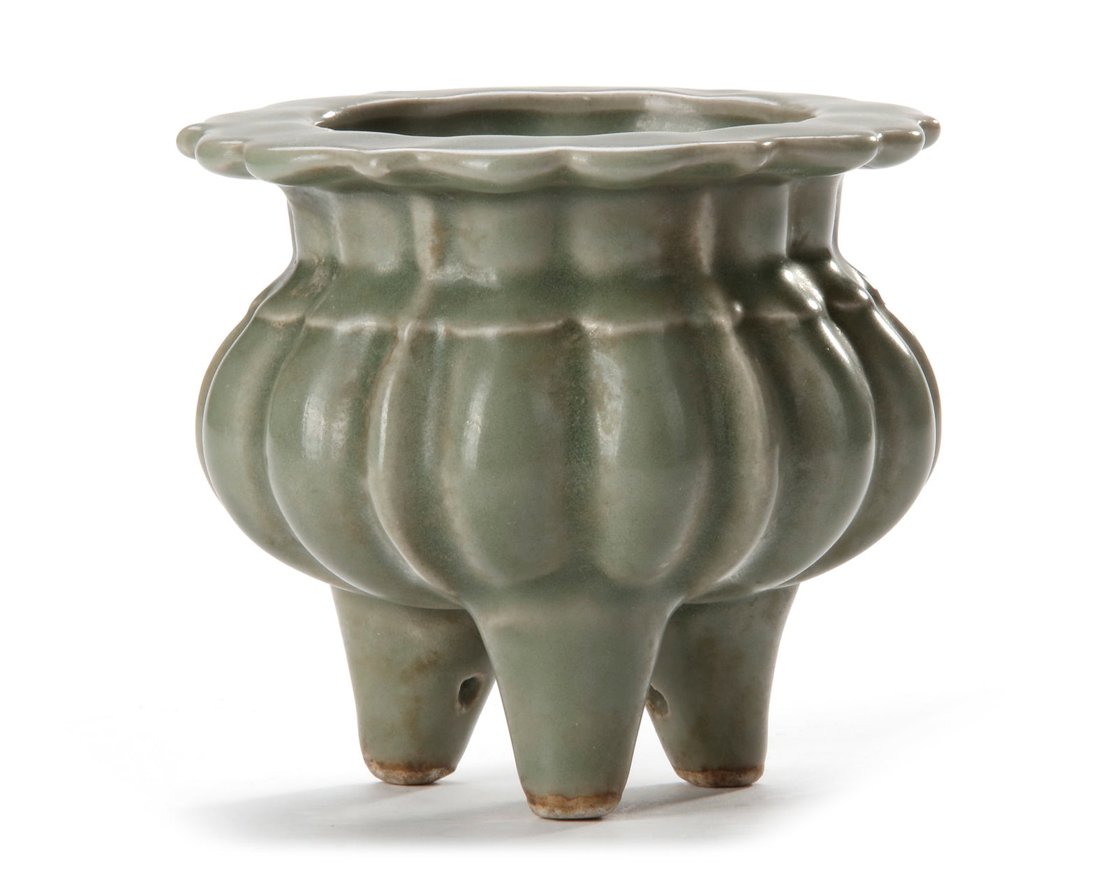 A CHINESE LOBED LONGQUAN TRIPOD CENSER, MING DYNASTY (1368-1644): The compressed body is raised on three short feet and has a flat everted barbed rim, lobed body and neck, with three narrow flanges. The censer is covered overall with a sea-green glaze of even tone. 