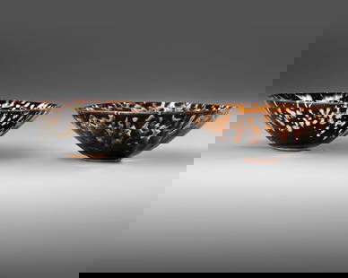 TWO CHINESE 'TORTOISESHELL' GLAZED BOWLS, QING DYNASTY (1644–1911): Two Chinese porcelain bowls with flared sides, each covered with a glassy russet glaze splashed yellow or cream white tear-drops, falling short to the unglazed footing.Height: 5.2 cm. Diameter: 15.5 c