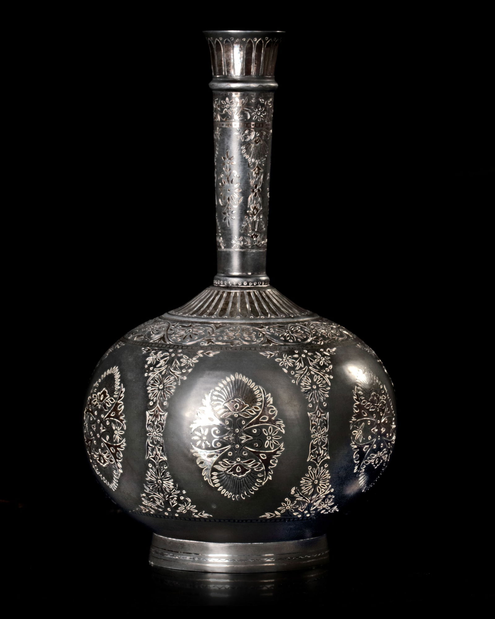 AN INDIAN SILVER-INLAID ALLOY BIDRI FLASK (SURAHI), DECCAN, 20TH CENTURY: A silver-inlaid alloy Bidri flask (surahi) of bulbous form on a splayed foot with long flaring neck, profusely inlaid with silver with an interlace of vines and foliate friezes.Height: 25 cm.