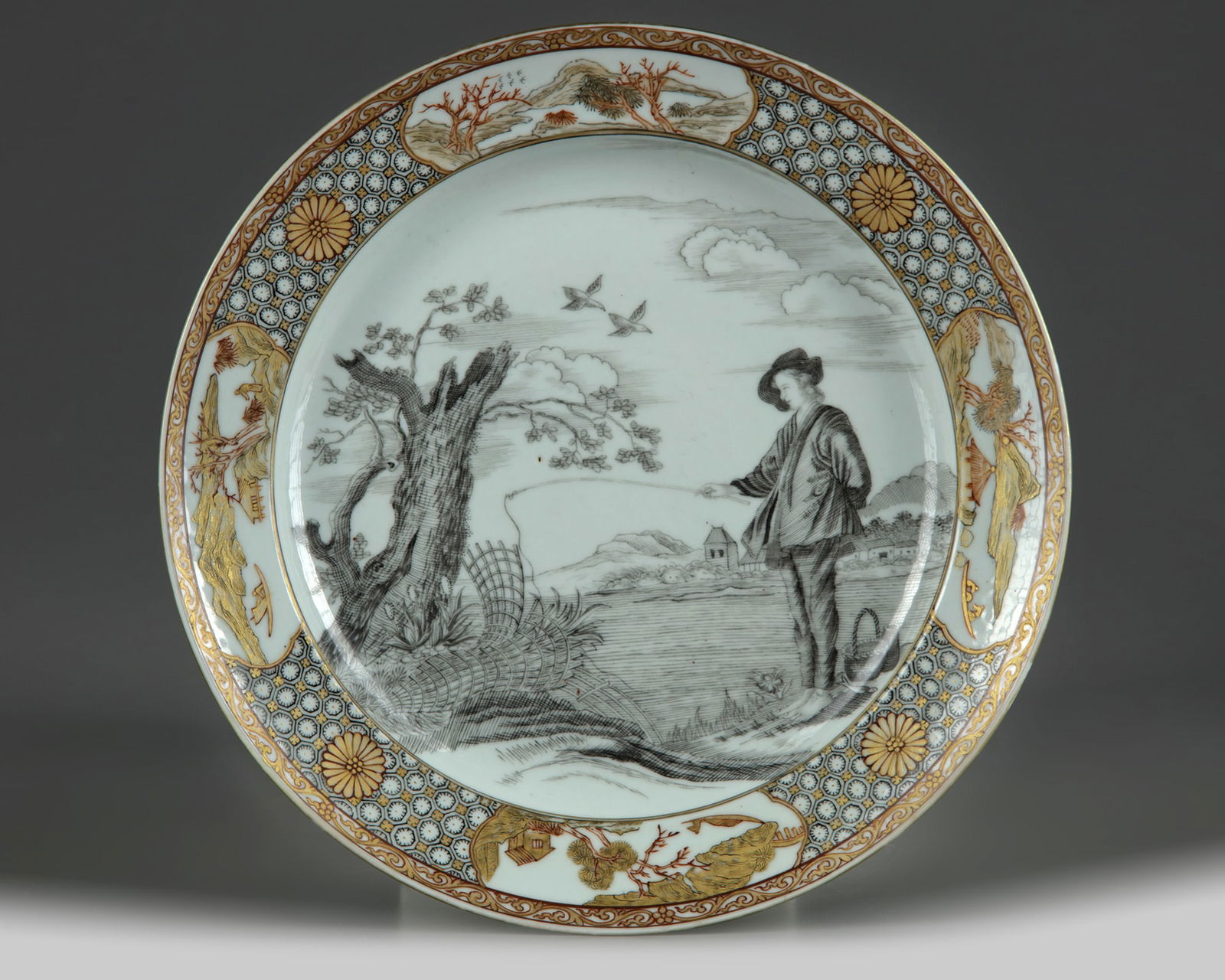 A CHINESE EN GRISAILLE AND GILT-DECORATED 'FISHERMAN' DISH, QING DYNASTY (1644-1911): The dish is decorated to the centre en grisaille after the painting of 'Le Pêcheur' by Abraham Bloemaert with a Dutch fisherman standing on a riverbank holding a pole. The scene is surrounded by land