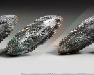 A PAIR OF ROMAN BRONZE AND SILVERED "FACE OF FEMALE" TERMINALS, CIRCA 2ND-3RD CENTURY AD: A cast bronze of two female head terminals probably for a chair or furniture. Left to right: 6.5 cm., 5.5 cm. length.PROVENANCE Private collection, Germany