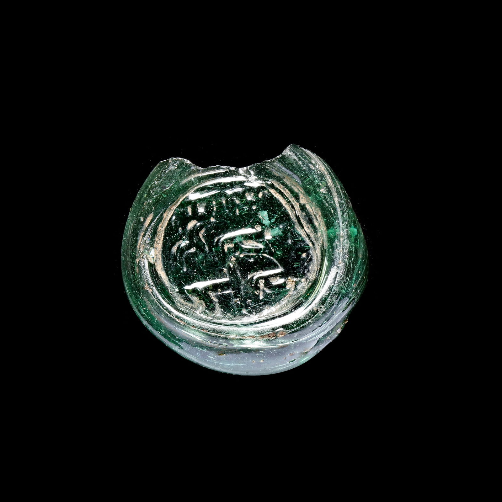 AN EARLY ISLAMIC GLASS VESSEL STAMP, 10TH-11TH CENTURY: A glass vessel stamp in the name of the maker "Yazid Bin Tamim", moulded and stamped, transparent dark-green in colour. 11.668 g., 30 mm.
