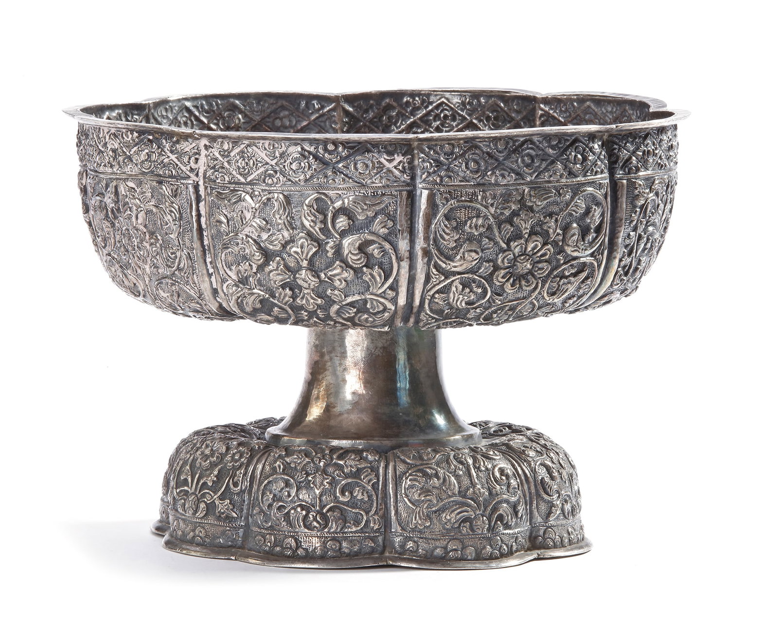 A MALAY SILVER BOWL, 19TH CENTURY: Richly decorated with floral and foliate motifs in high relief, standing on a matching ornate pedestal base. Diam 24 cm. Height 17 cm. 909 gr.