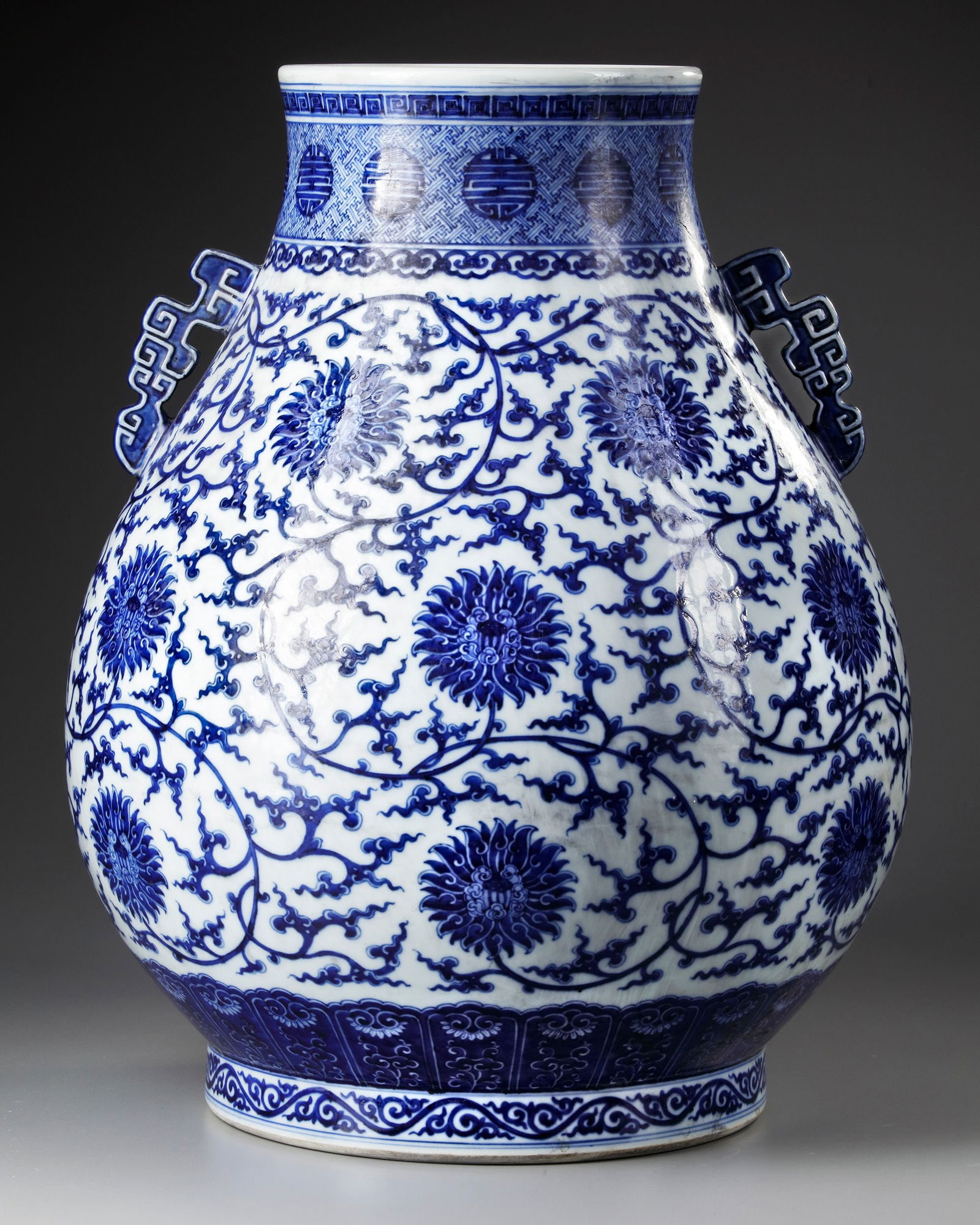 A LARGE CHINESE BLUE AND WHITE HU VASE, 19TH-20TH CENTURY: A large Chinese porcelain pear-shaped vase, heavily potted with a wide generous body and two squared archaistic pierced handles on the shoulder, the body painted with a continuous meander of tendrils