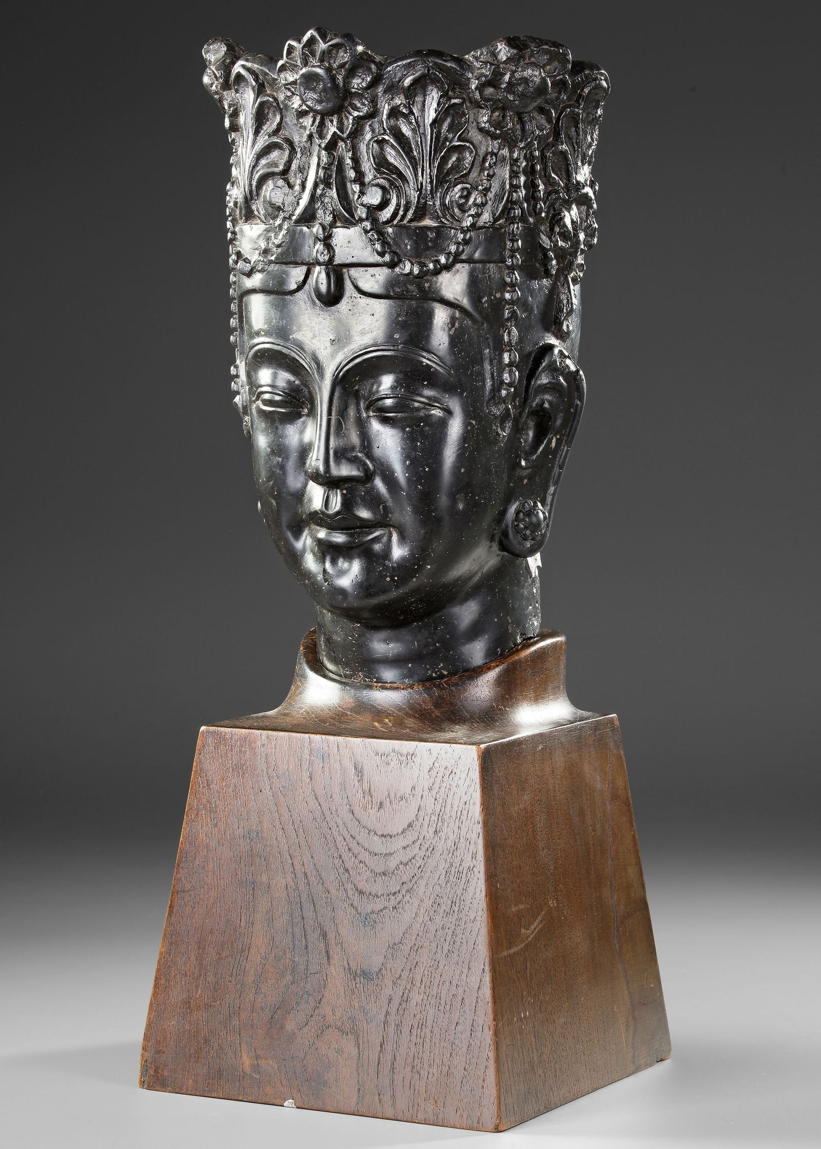 A CHINESE STONE HEAD OF A BODHISATTVA, SONG DYNASTY OR LATER: A finely carved stone head of a Bodhisattva, depicting a serene expression with downcast eyes and a gentle smile. The figure wears an elaborate floral crown adorned with beads and ornaments. The sculp