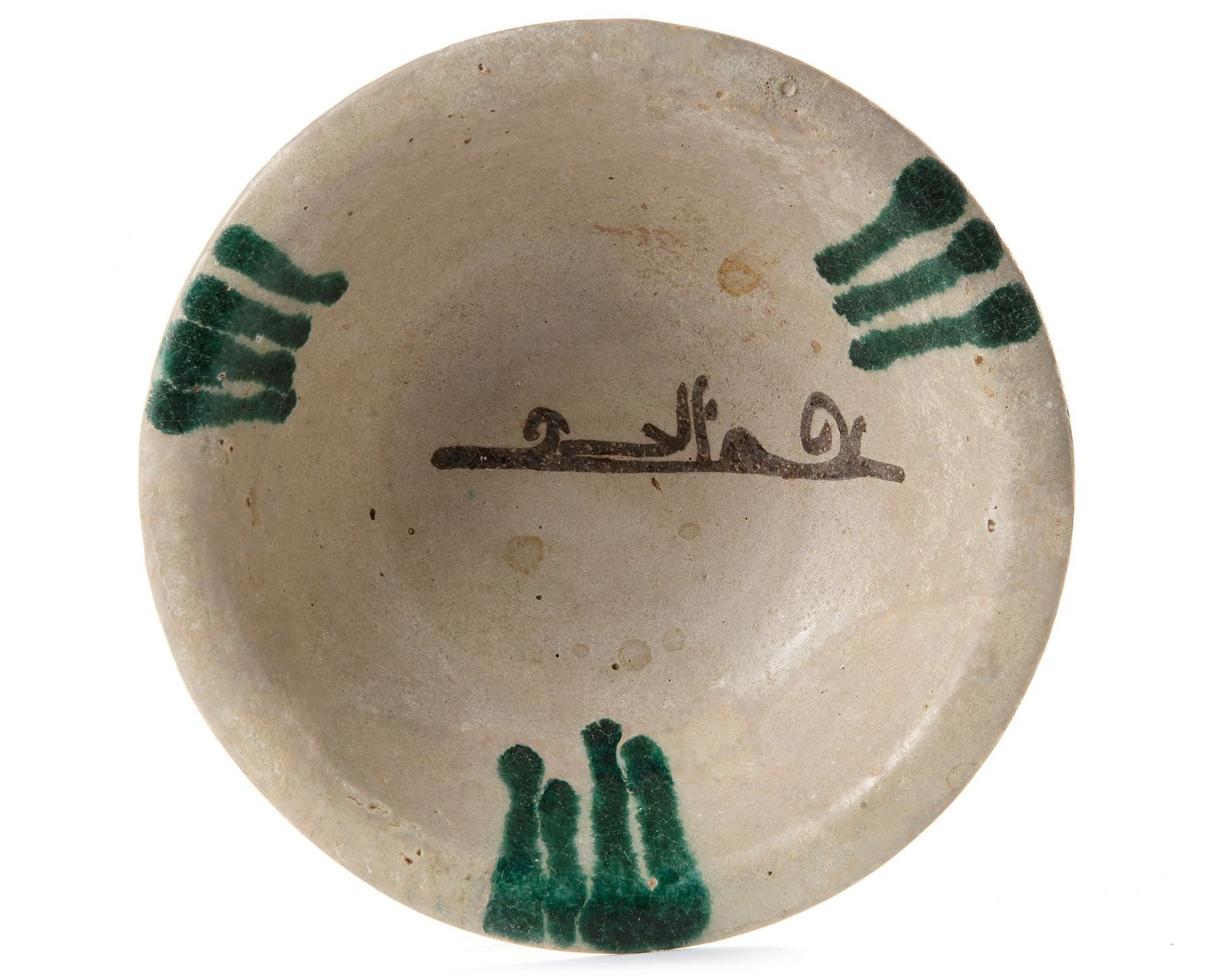 AN ABBASID TIN GLAZED POTTERY BOWL, MESOPOTAMIA, 9TH CENTURY: Of rounded form with everted lip on short foot, the light grey interior painted in brown with a single phrase of flowing Kufic, extending from the edges above and below are three green dashes and